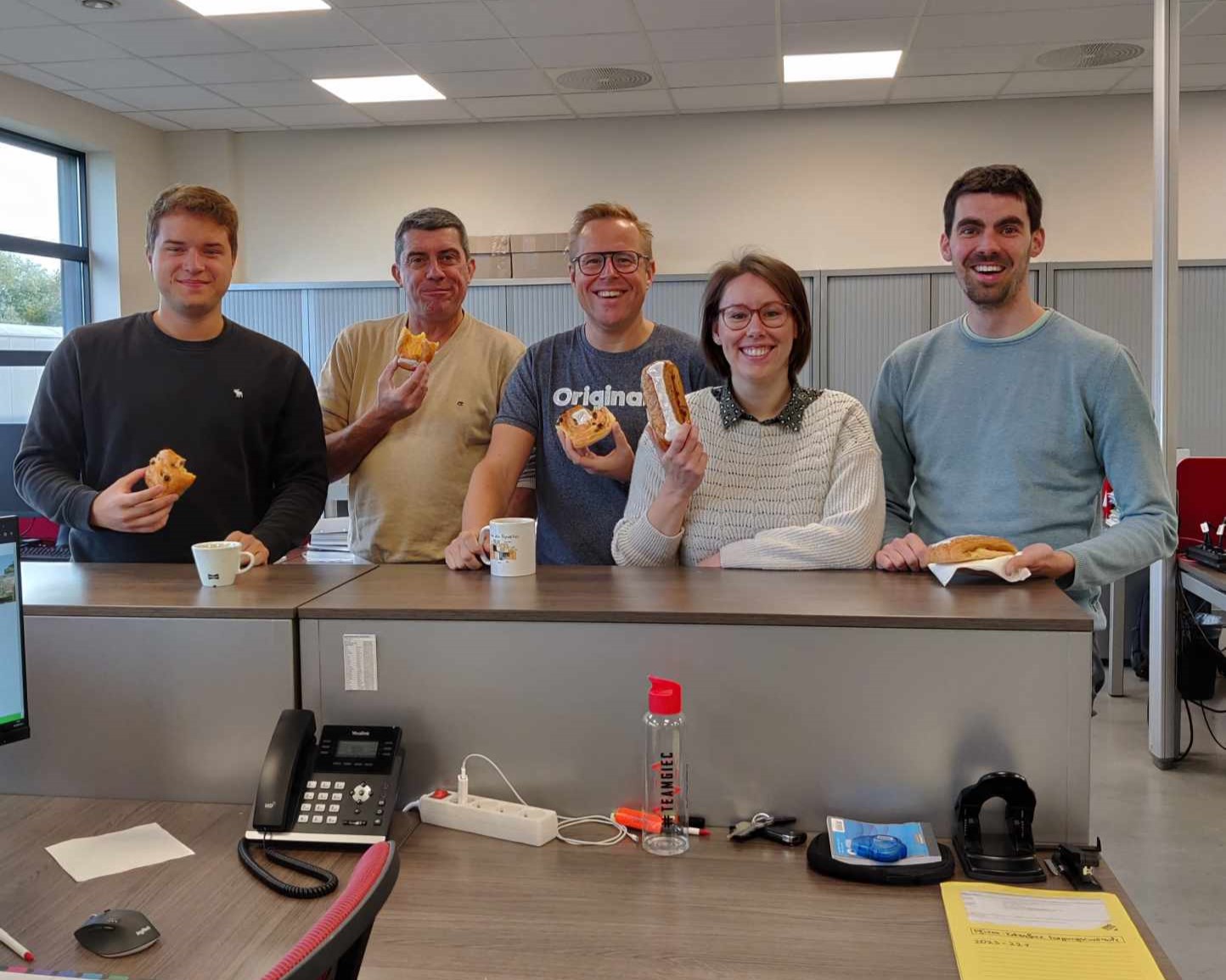4 collega's van Team GIEC eten koffiekoeken voor de Week van het Werkgeluk